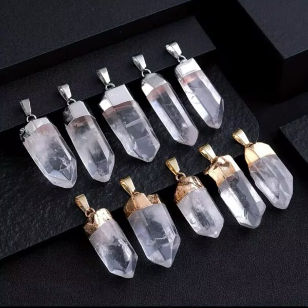 Clear quartz crystal pendants with silver-tone caps arranged in two rows on a black display backdrop, showcasing multiple shapes and facets.