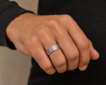 Close-up of a hand wearing a silver multi-band ring on the ring finger; dark sleeve visible in the background.
