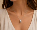 Close-up of a silver layered ring pendant on a delicate chain resting on a woman's collarbone area.