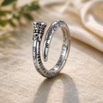 Two silver rings with engraved text and decorative patterns resting on sand.