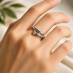 Close-up of a hand wearing two silver, dotted snake-stack rings with a small yellow gemstone bead on the bottom ring