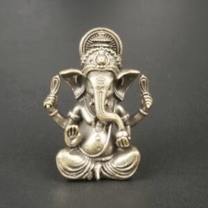 Metallic statue of the Hindu god Ganesha, seated cross-legged with four arms and a crown against a dark background